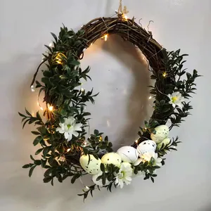 Dettaglio della ghirlanda pasquale con uova macchiate, fiori bianchi e luci LED calde