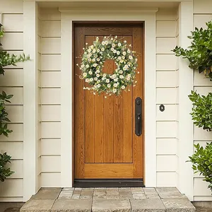 Detailed view of artificial daisy and eucalyptus wreath on a rustic dark wood door