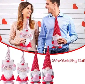 Close-up of Valentine gnome plush dolls with knit hats holding hearts and envelopes