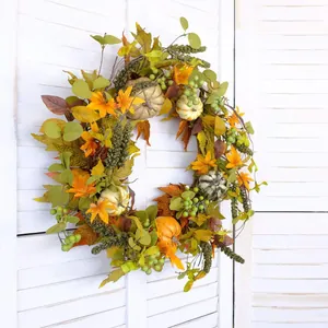 Fall wreath with pumpkins, maple leaves and green berries on a white shutter background