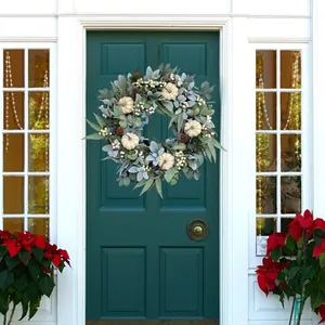 Autumn wreath with white pumpkins and pine cones on a dark green front door