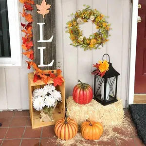 Detail of autumn porch decor with pumpkin wreath, vintage lantern, and maple leaf accents