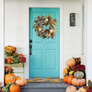 Close-up of fall wreath with faux pumpkins and maple leaves on a turquoise door