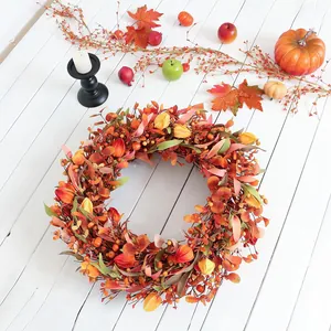 Herbstkranz mit orangefarbenen Beeren und Ahornblättern auf weißem Holzhintergrund