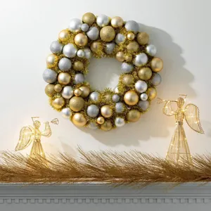 Close-up of a festive Christmas wreath with gold and silver ornaments on a white wall