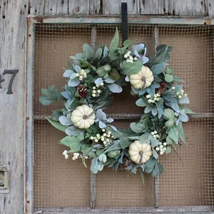 Detail of fall wreath with white pumpkins and eucalyptus on a rustic wooden door