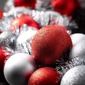 Close-up of sparkling red and silver Christmas glitter ball ornaments with silver tinsel