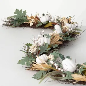 Ghirlanda autunnale con zucche bianche, foglie di acero e bacche per decoro porte
