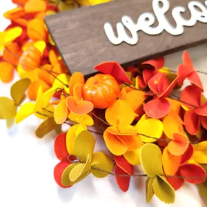 Close-up of autumn wreath featuring mini pumpkins and welcome wood sign decoration