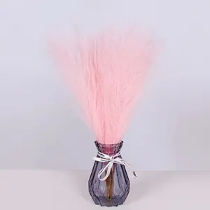 Detail of pink faux pampas grass in a grey glass vase with decorative ribbon bow