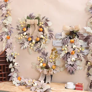 Herbstlicher Kranz mit weißen Kürbissen, Ahornblättern und Beeren an einer beigen Wand