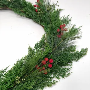Detailed close-up of dense artificial pine needles and bright red berries on a festive wreath