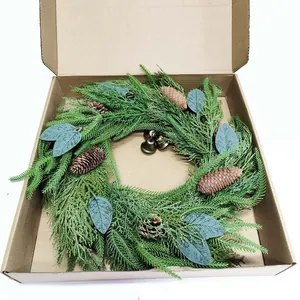 Detail of an evergreen Christmas wreath with pine cones and bronze bells in a kraft box