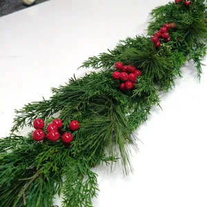 Close-up of artificial Christmas garland with green pine needles and red berries decor