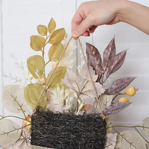 Herbstkranz mit weißen Kürbissen Ahornblättern und Beeren in einem geflochtenen Korb