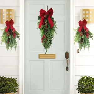 Christmas teardrop swag with red bow and pine cones hanging on a white door
