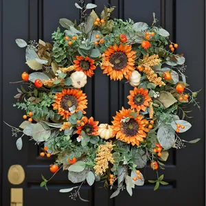 Autumn wreath with orange sunflowers, pumpkins and eucalyptus on a black wooden door