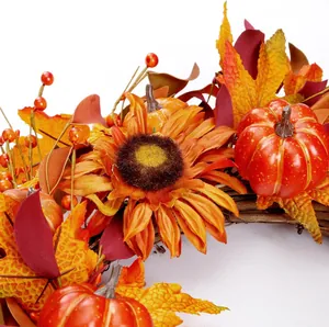 Fall wreath with orange sunflower, pumpkins, and maple leaves on natural vine base