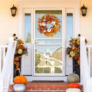 Autumn wreath with pumpkins and maple leaves hanging on a white front door