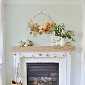 Fall farmhouse wreath with white wood beads, pumpkins, and berries over a white fireplace