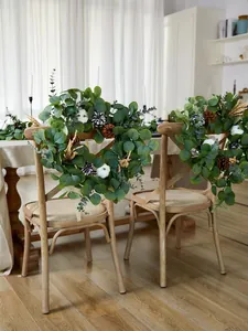 Detalle de guirnaldas de eucalipto con calabazas y piñas en respaldos de sillas