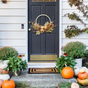 Close-up of wood bead pumpkin wreath with autumn maple leaves on a black door
