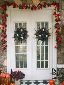 Detail of gothic Halloween wreath with black maple leaves and white skulls on double doors