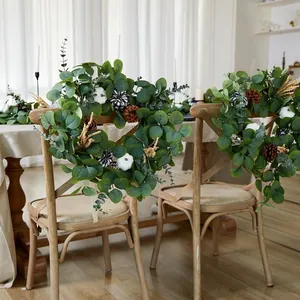 Guirnalda de otoño de eucalipto con calabazas blancas y piñas en sillas de madera