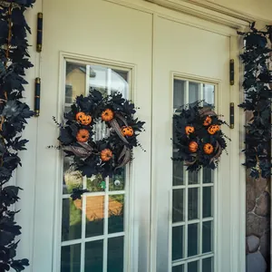 Symmetric Halloween wreaths with black maple leaves and orange pumpkins on white double doors