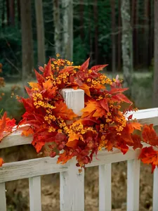 Close-up of autumn wreath with vibrant maple leaves on a white wooden fence post