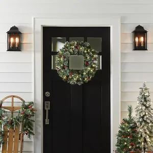 Christmas wreath with pine needles, red berries and warm LED lights on a black door