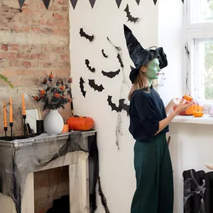 Détail déco Halloween avec vase blanc, branches de citrouille noires et stickers de chauve-souris