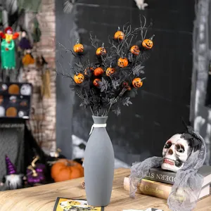 Branches d'Halloween avec feuilles d'érable noires et citrouilles orange dans un vase