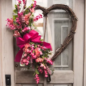 Heart-shaped rattan wreath with pink faux flowers and a magenta silk bow for home decor