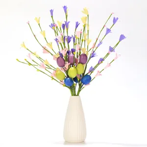 Detail view of Easter floral stems with colorful eggs and wildflowers in a white vase