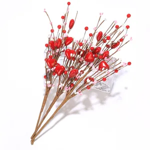Nahaufnahme künstlicher herzförmiger roter Beeren und rosa Blütenknospen für Deko