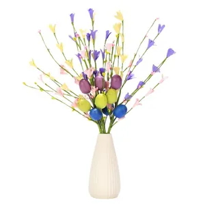 Artificial Easter floral stems with colorful eggs and wildflowers in white striped vase