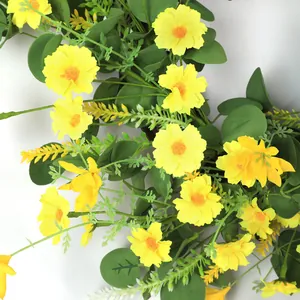 Close-up of artificial yellow daisies and green foliage on a wall hanging decoration