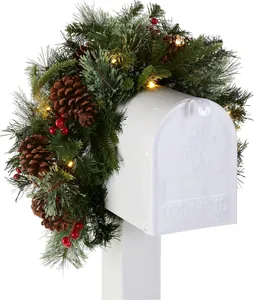Close-up of lighted Christmas garland with pine cones and berries on a mailbox