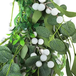 Detailed view of artificial eucalyptus leaves and white berries with LED string lights
