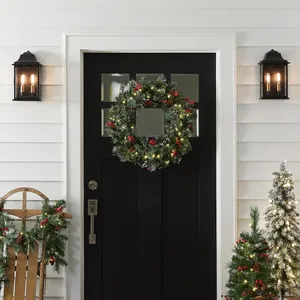 Illuminated Christmas wreath with red berries and LED lights hanging on a black front door