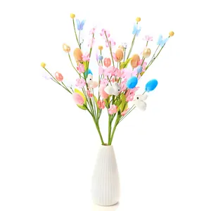 Close-up of Easter branch decor with colorful eggs, pink flowers and rabbits in white vase