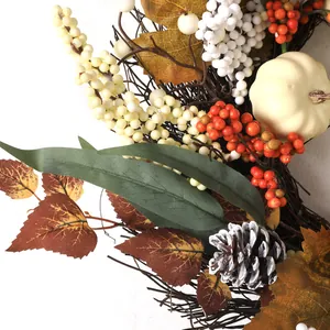 Autumn wreath with white pumpkins, maple leaves, berries and pine cones on rattan base