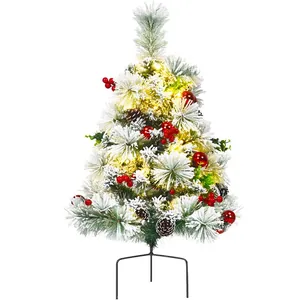 Green flocked Christmas tree with warm LED lights, pine cones, and red berries on a metal stand