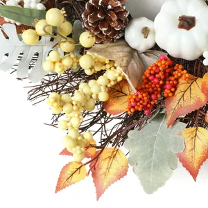Dettaglio ghirlanda autunnale con zucche bianche, pigne e foglie di acero vivaci