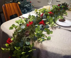 Close-up of artificial eucalyptus garland with red berries and pine cones on a table