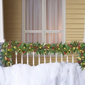 Illuminated Christmas garland with pine cones and red berries on a balcony railing