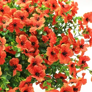 Macro shot of bright orange artificial flower petals with realistic dark texture and green leaves