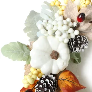 Dettaglio di zucca bianca, pigne e bacche su ghirlanda autunnale di foglie d'acero