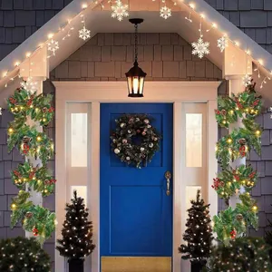 Detail of pre-lit Christmas garland with pine needles, berries, and cones on front porch